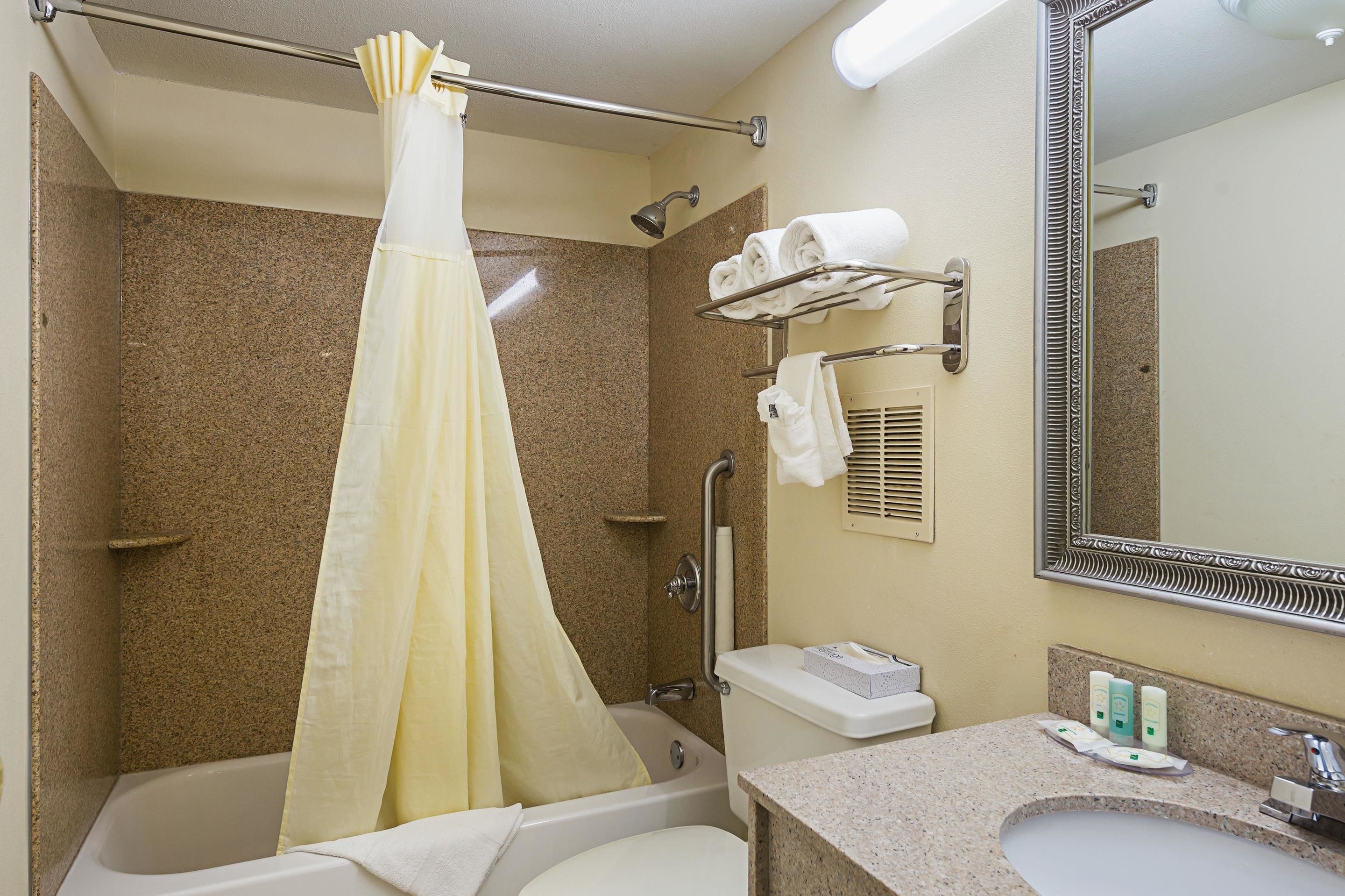 A bathroom with a bathtub, shower, toilet, sink, and a mirror.