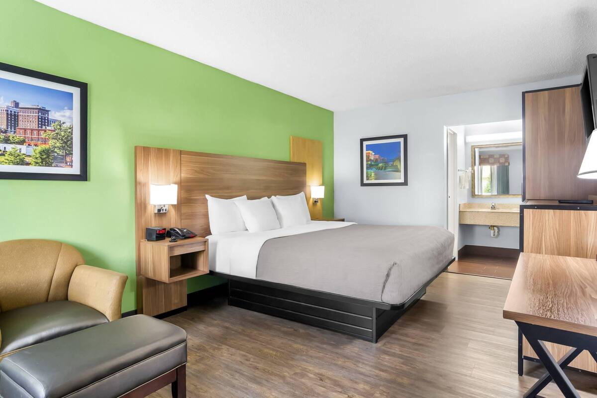 A hotel room with a bed, a desk, a chair, and a TV.