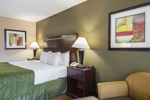 Habitación de hotel con una cama, dos lámparas de noche, una mesita de noche con teléfono y reloj, y una silla.