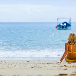 Na praia, areia branca, espreguiçadeiras, toalhas de praia