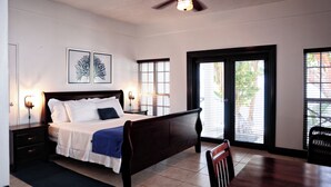 A bedroom with a bed, nightstands, a desk, and a chair. There are windows with blinds and a ceiling fan. - Blue Waters Inn (Speyside)