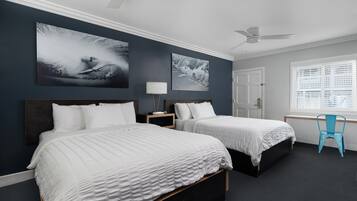 A bedroom with two beds, a desk, a chair, and large wall art.