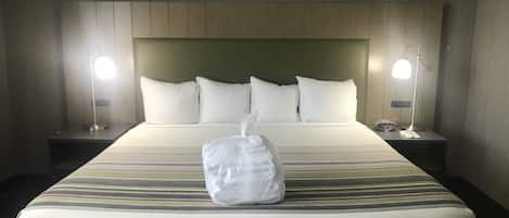 A hotel room with a large bed, two bedside lamps, and a headboard with a wooden panel design.