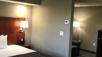 Habitación de hotel con una cama grande, un cabecero de madera, dos lámparas de noche, un escritorio pequeño y una silla.