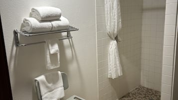 Un baño con ducha, perchero, silla y suelo de baldosas.