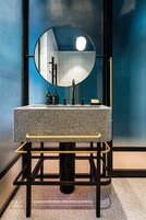 Un bagno con un lavandino in granito, uno specchio rotondo e una cornice nera.