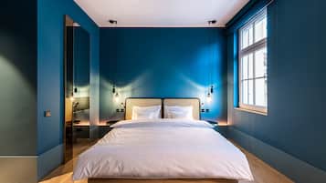 A modern bedroom with a large bed, a window, and a mirror.