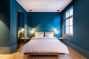 Een moderne slaapkamer met een groot bed, een raam en een spiegel.