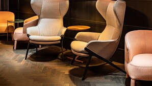 A modern lounge area with three upholstered chairs, a small round table, and wall-mounted lamps. - Hotel Maximilian (Prague)