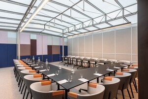 Una sala conferenze con un lungo tavolo, diverse sedie e un soffitto in vetro.