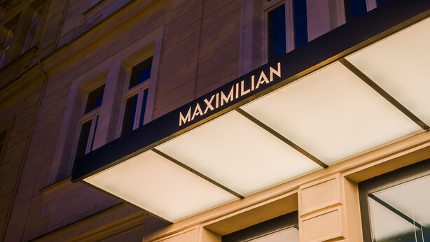 A building facade with the name "MAXIMILIAN" illuminated above the entrance. - Hotel Maximilian (Prague)