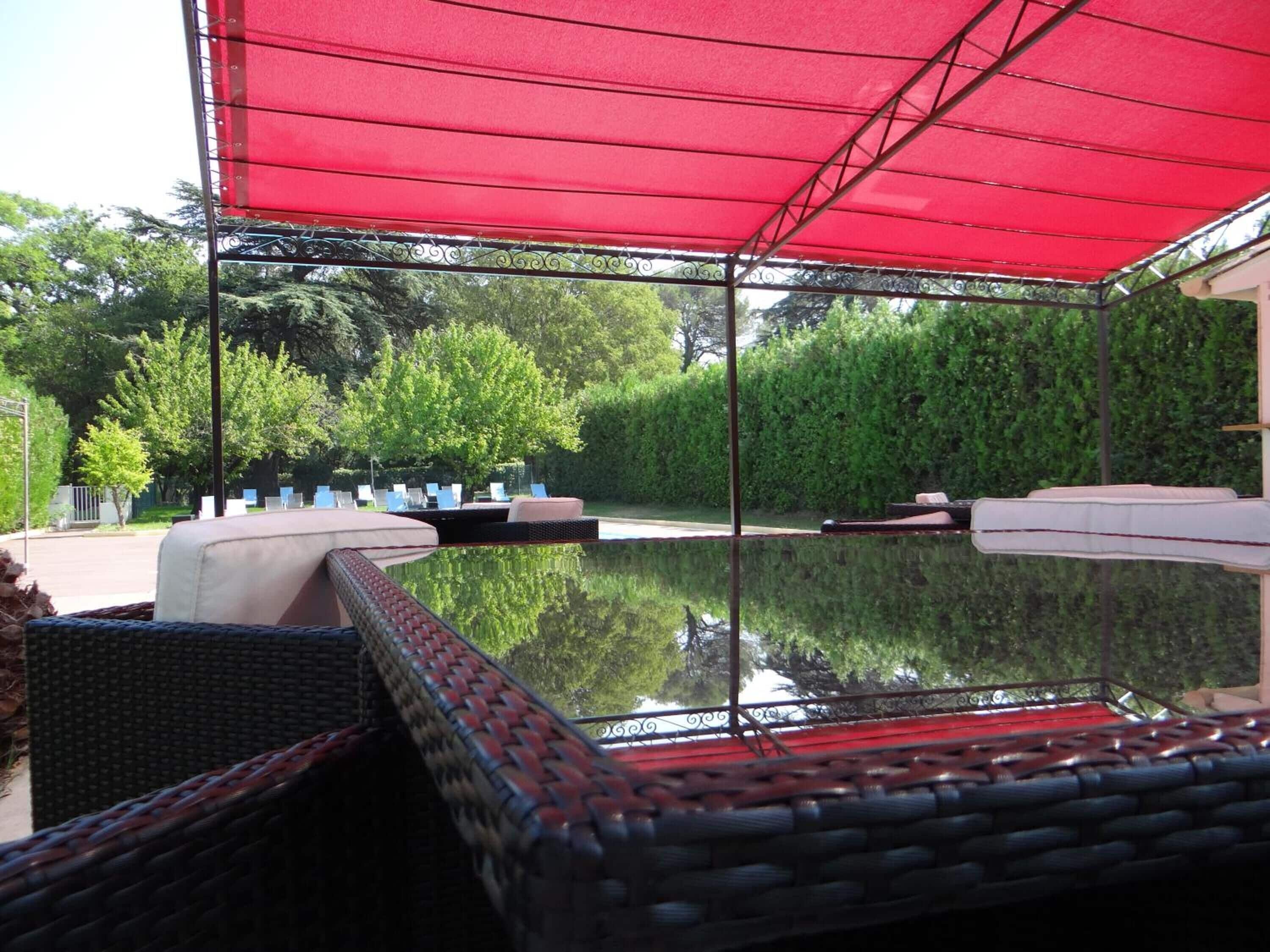A covered outdoor seating area with wicker furniture and a pool.