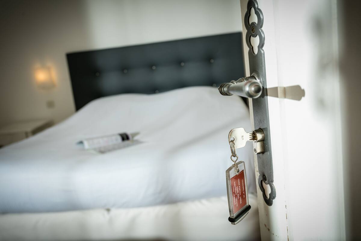 Un lit avec un matelas blanc et une télécommande posée dessus.