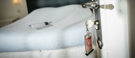A bed with a white mattress and a remote control on it.
