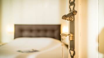 A close-up of a bed with a headboard, a bedside table, and a wall-mounted light fixture.