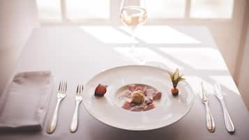 A table set with a plate of food, a glass of white wine, and silverware.