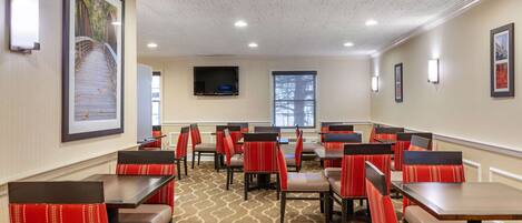 A restaurant with booths and tables, a patterned carpet, and framed pictures on the walls.