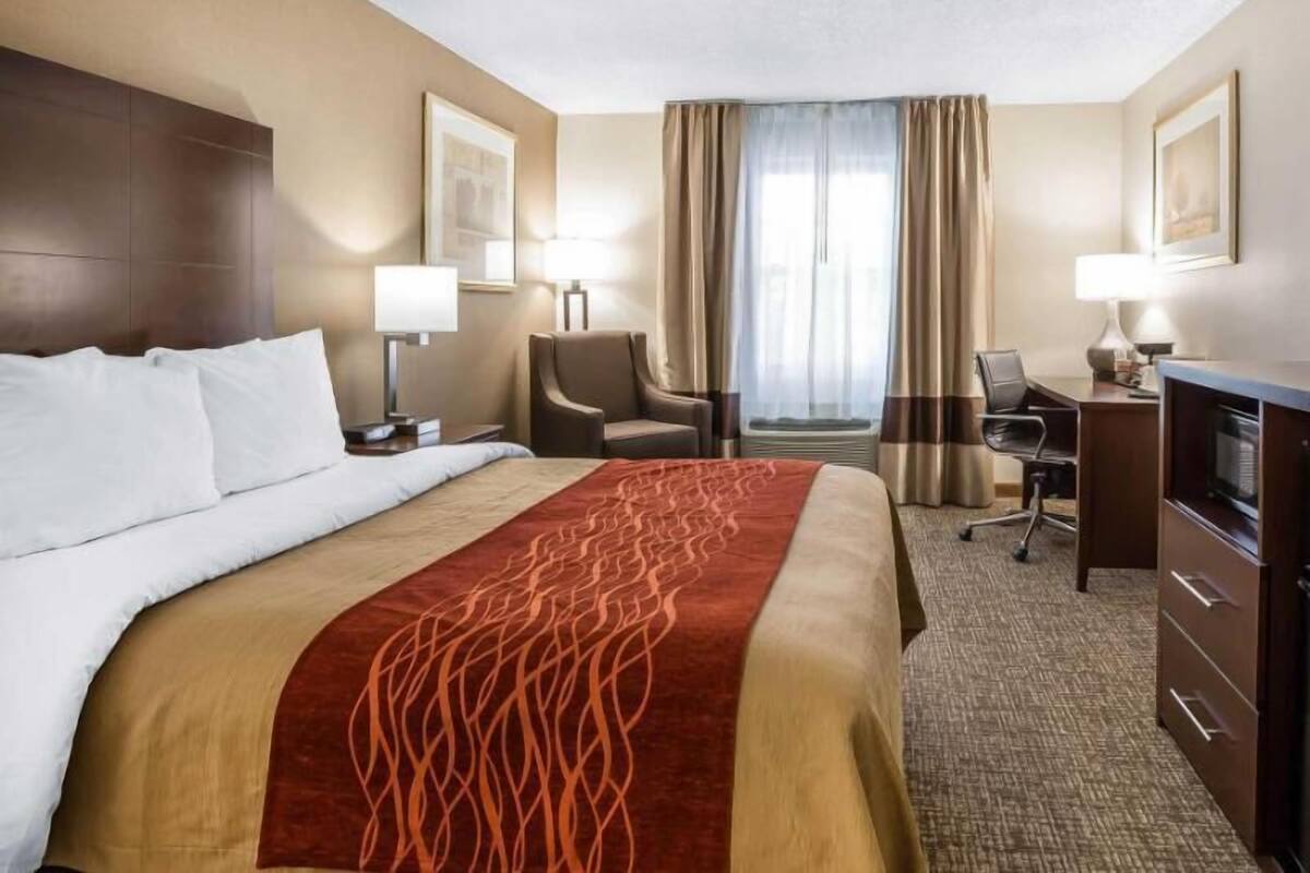 Une chambre d’hôtel avec un lit, un bureau, une chaise et des rideaux.
