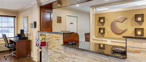 A reception area with a stone wall, a wooden reception desk, a phone, and a vending machine.