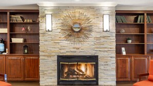 A cozy living room with a fireplace, wooden bookshelves, and comfortable seating.