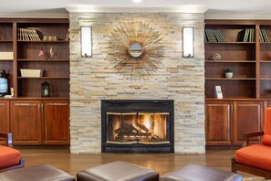 A cozy living room with a fireplace, wooden bookshelves, and comfortable seating.