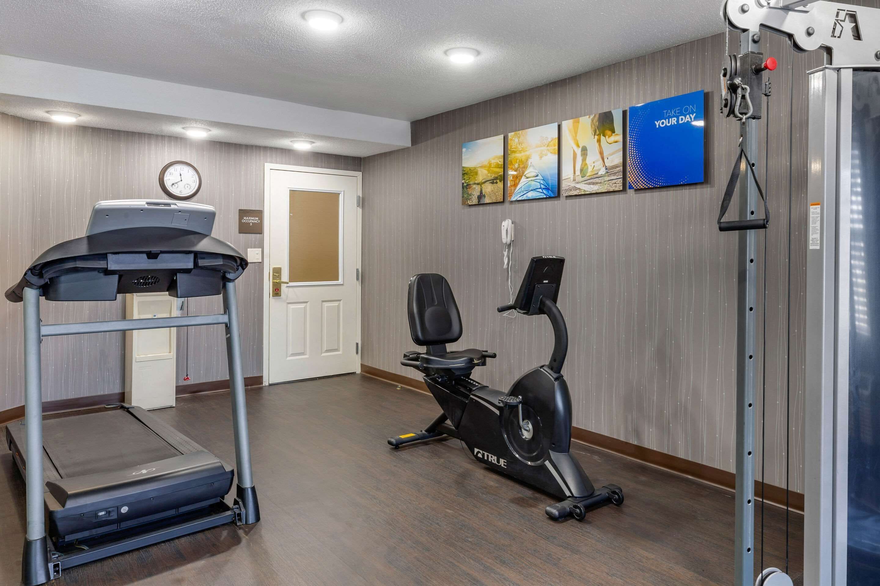 A fitness room with a treadmill, an elliptical, and a wall-mounted phone.
