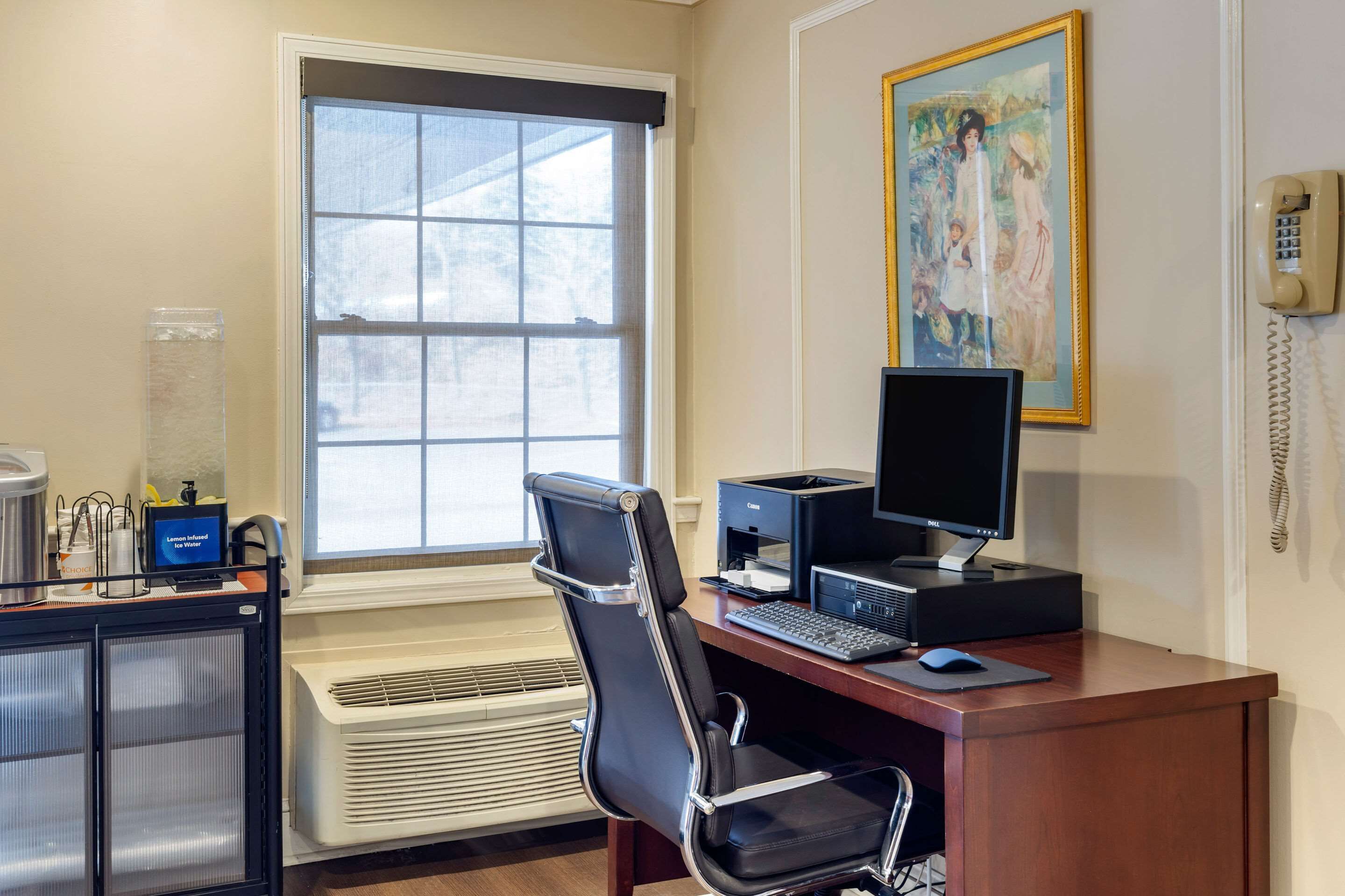 A modern office with a large window, a desk with a computer, a chair, and a painting on the wall.