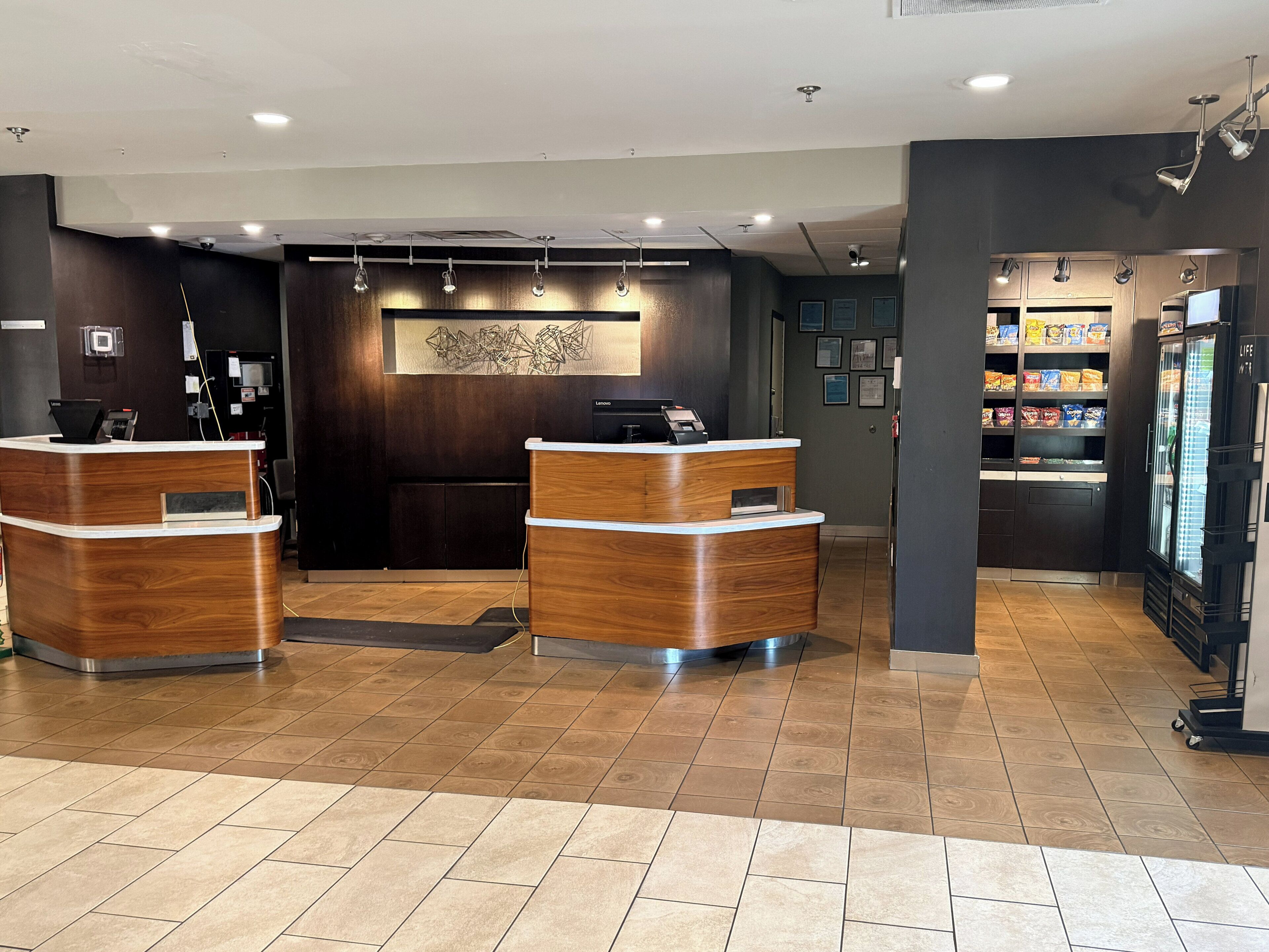 Un espace d’accueil comprenant deux comptoirs de réception en bois, une œuvre d’art accrochée au mur et un réfrigérateur rempli de collations.