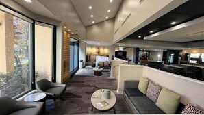 A modern hotel lobby with seating areas, a reception desk, and a bar. - Hotel Preston (Montgomery)
