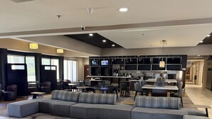 A modern hotel lobby with a seating area, a bar, and a kitchen. - Hotel Preston (Montgomery)