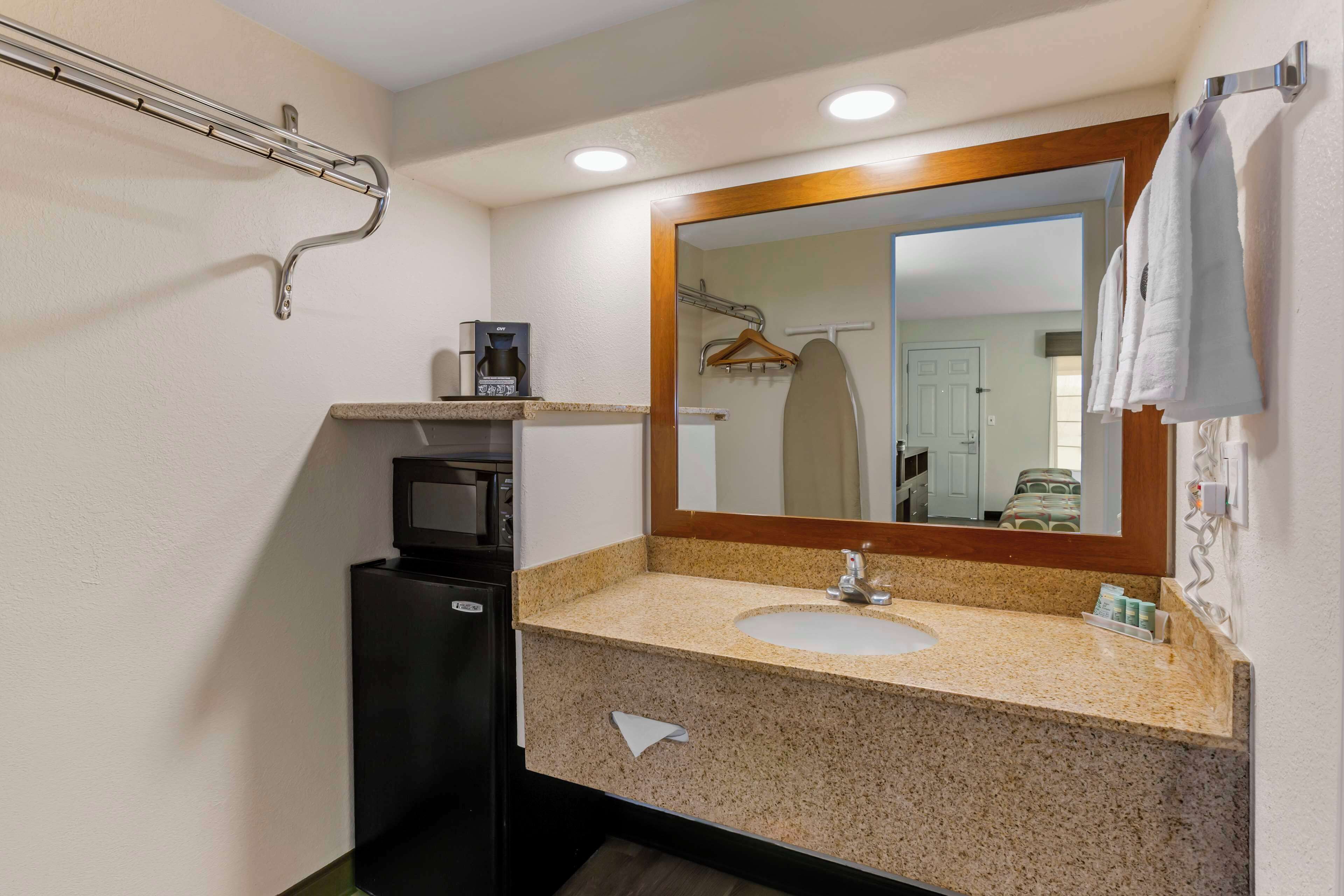 A bathroom with a sink, mirror, towel rack, and a coffee machine.