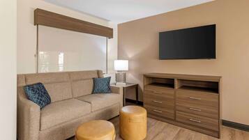 Una sala de estar moderna con sofá, otomanas, televisor y mueble.