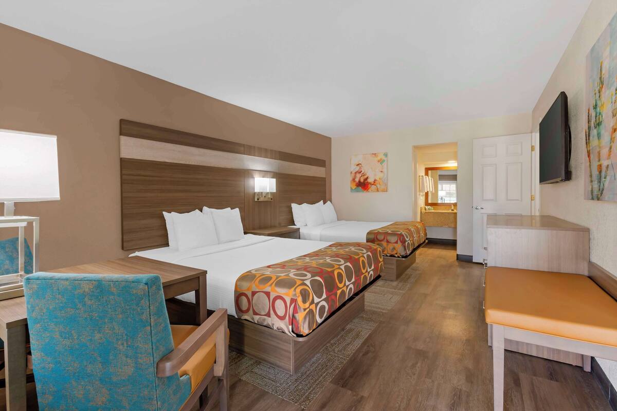 A hotel room with a large bed, a desk, a chair, and a television.