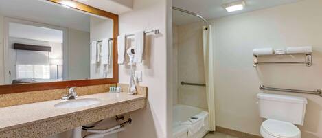Une salle de bain moderne équipée d’un lavabo, d’un miroir, d’un porte-serviettes, d’une douche et de toilettes.