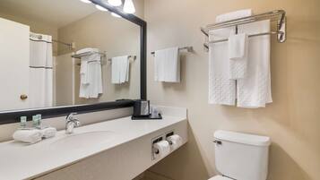 A modern bathroom with a large mirror, white sink, and towel rack.