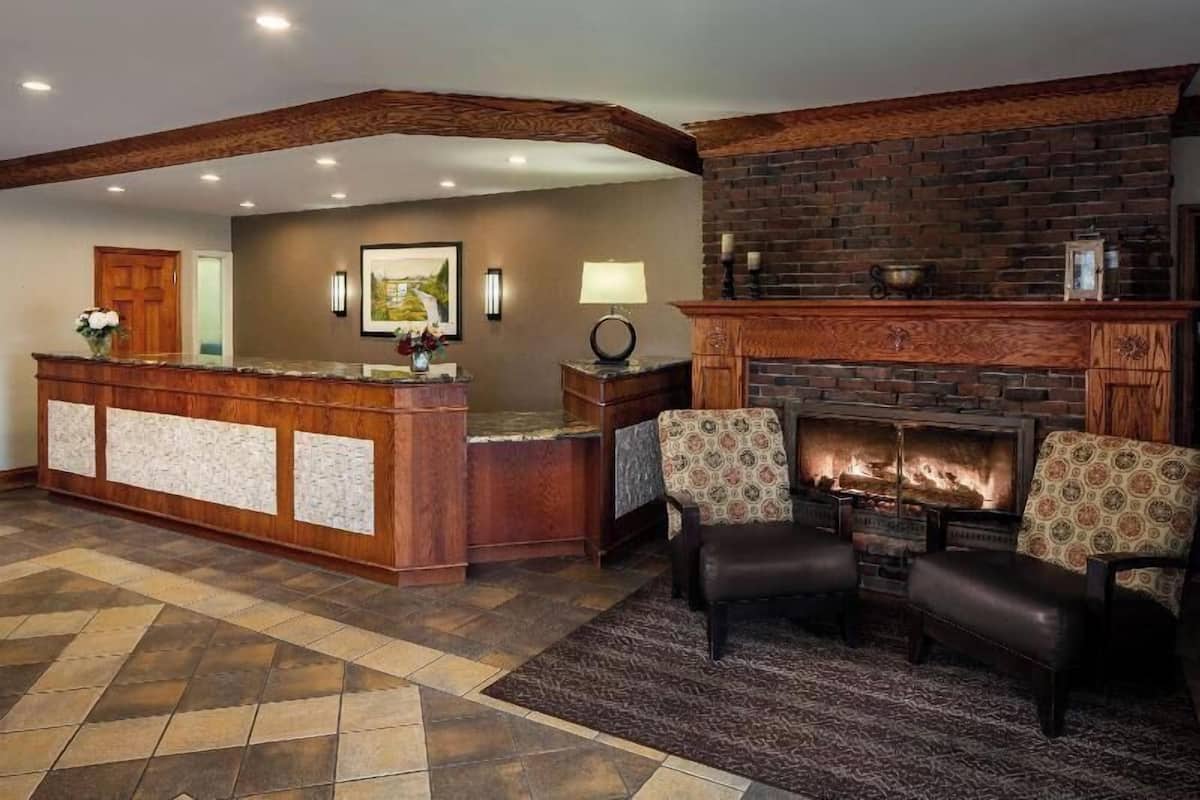 A reception area with a wooden reception desk, a fireplace, and two patterned armchairs.