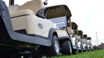Reihe von Golfcarts auf einer Rasenfläche.