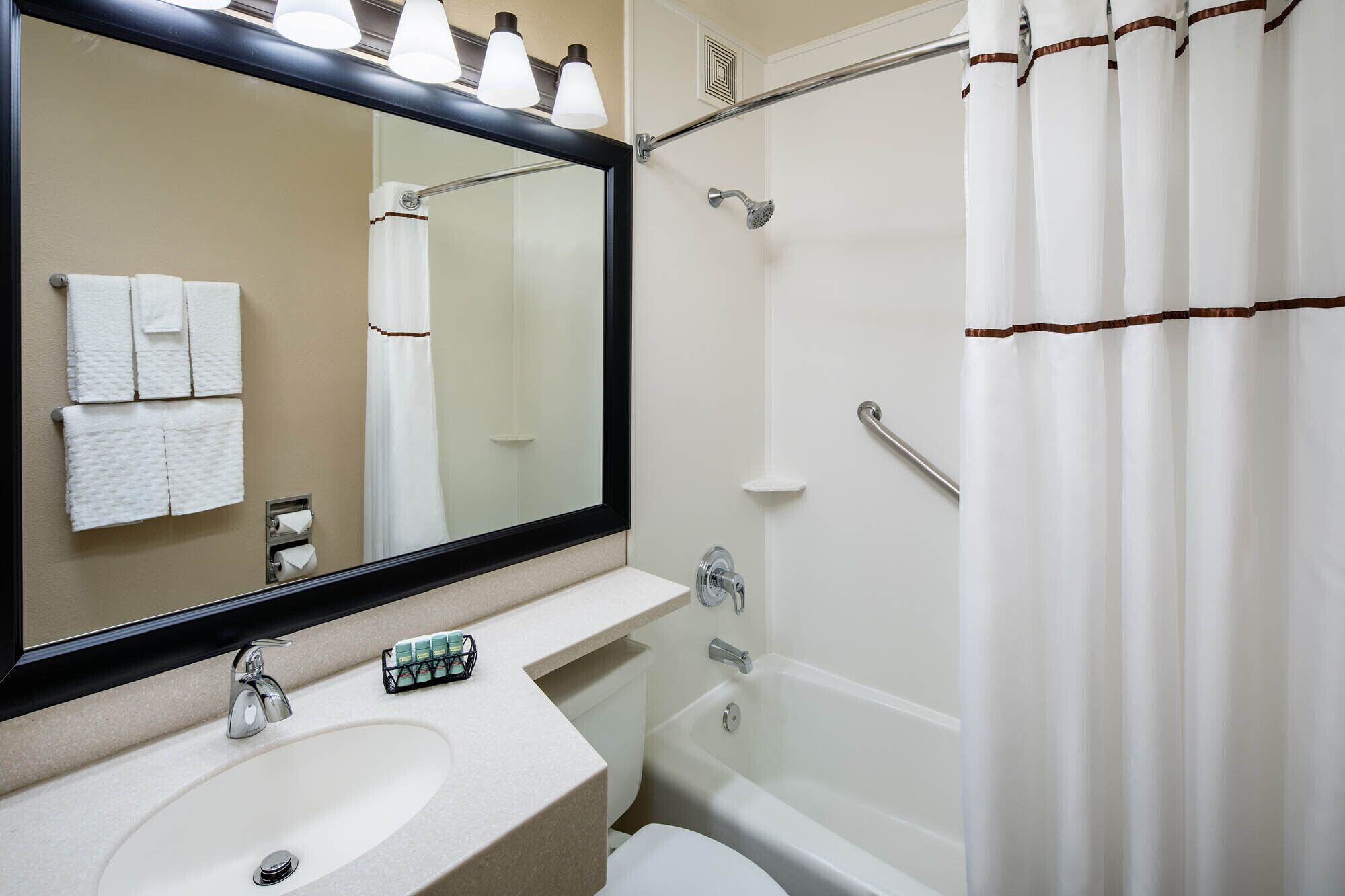 A bathroom with a sink, mirror, shower, and toilet.