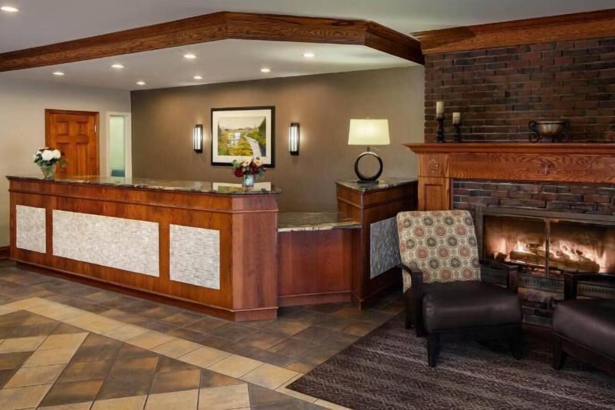A reception area with a wooden desk, a fireplace, and two patterned armchairs.