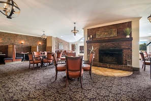 A spacious dining area with a brick fireplace, modern lighting fixtures, and a patterned carpet.