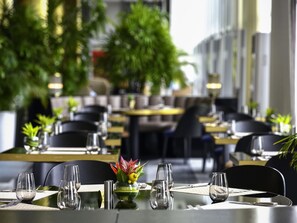 Ein Restaurant mit gedeckten Tischen, Stühlen und einer dekorativen Pflanzengirlande.