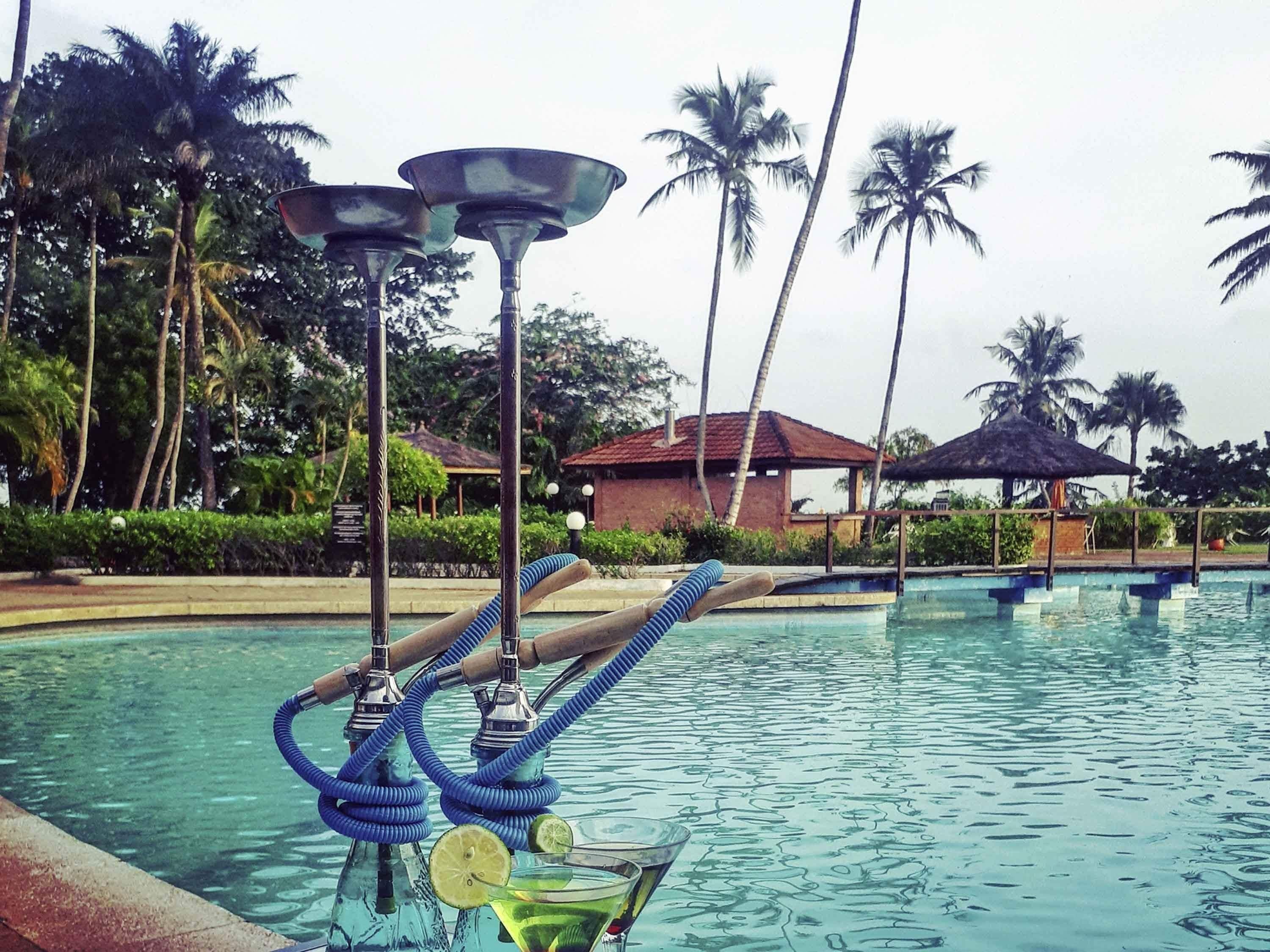 A pool with a water feature, palm trees, and a building in the background.
