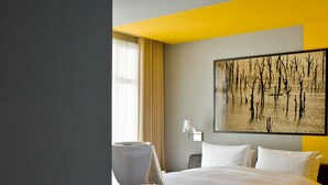 Une chambre d’hôtel avec un grand lit, une table de chevet, une lampe et un tableau au mur.