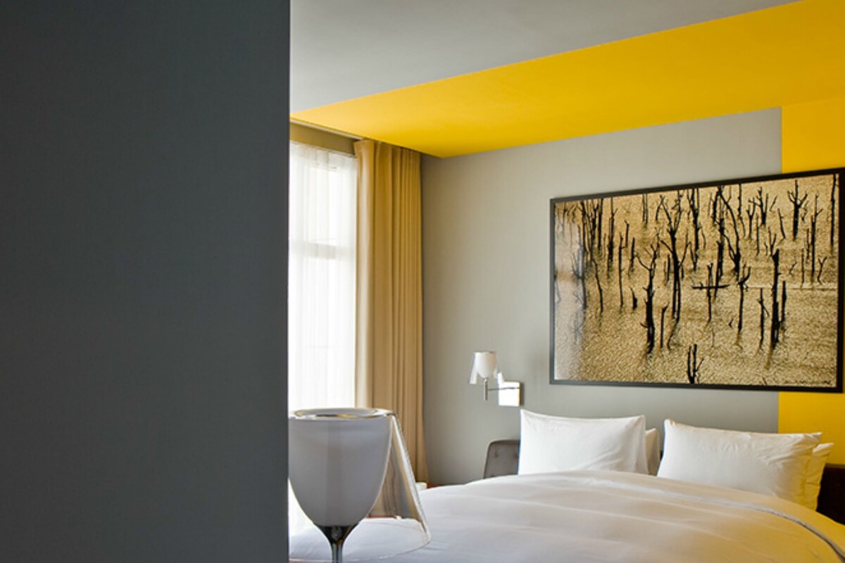 Une chambre d’hôtel avec un grand lit, une table de chevet, une lampe et un tableau au mur.