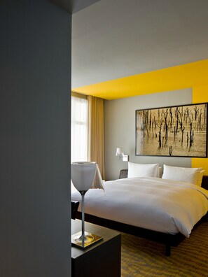 Une chambre d’hôtel avec un grand lit, une table de chevet, une lampe et un tableau au mur.