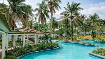Un resort con una piscina grande, palmeras y un área techada.