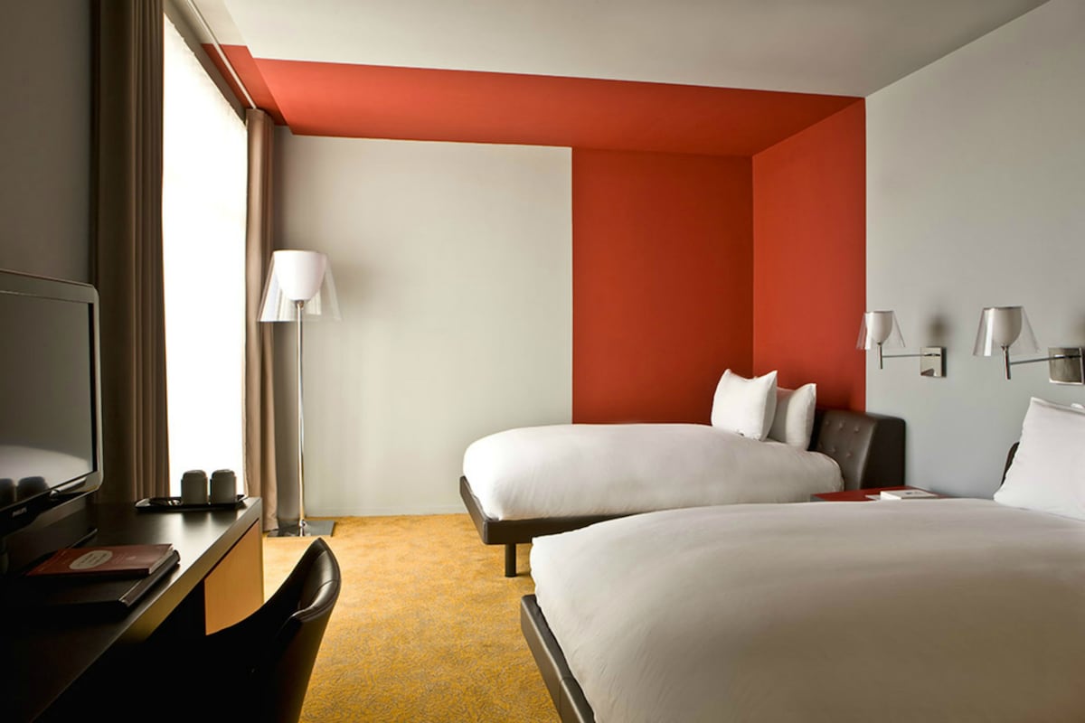 Une chambre d’hôtel avec deux lits, un bureau avec un ordinateur et une télévision.