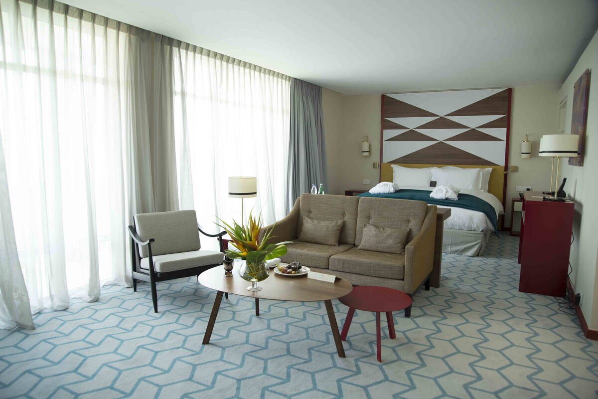 Une chambre d’hôtel avec un lit, un canapé, une petite table, une chaise et un bureau.