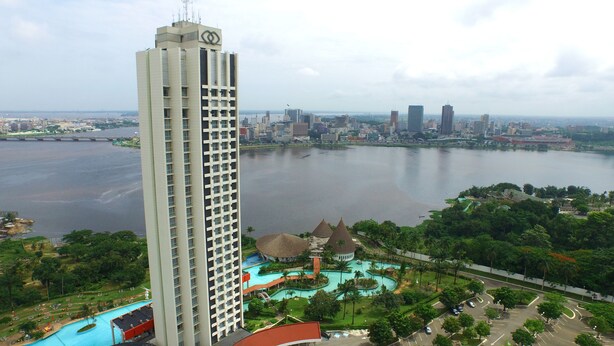 Un hôtel de grande hauteur doté d’une piscine et offrant une vue sur les gratte-ciel d’une ville, de l’autre côté d’une rivière.