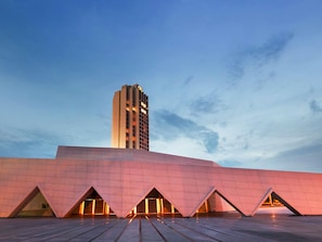 A modern building with a prominent tower and a flat roof with triangular structures. - Sofitel Abidjan Hotel Ivoire (Abidjan)
